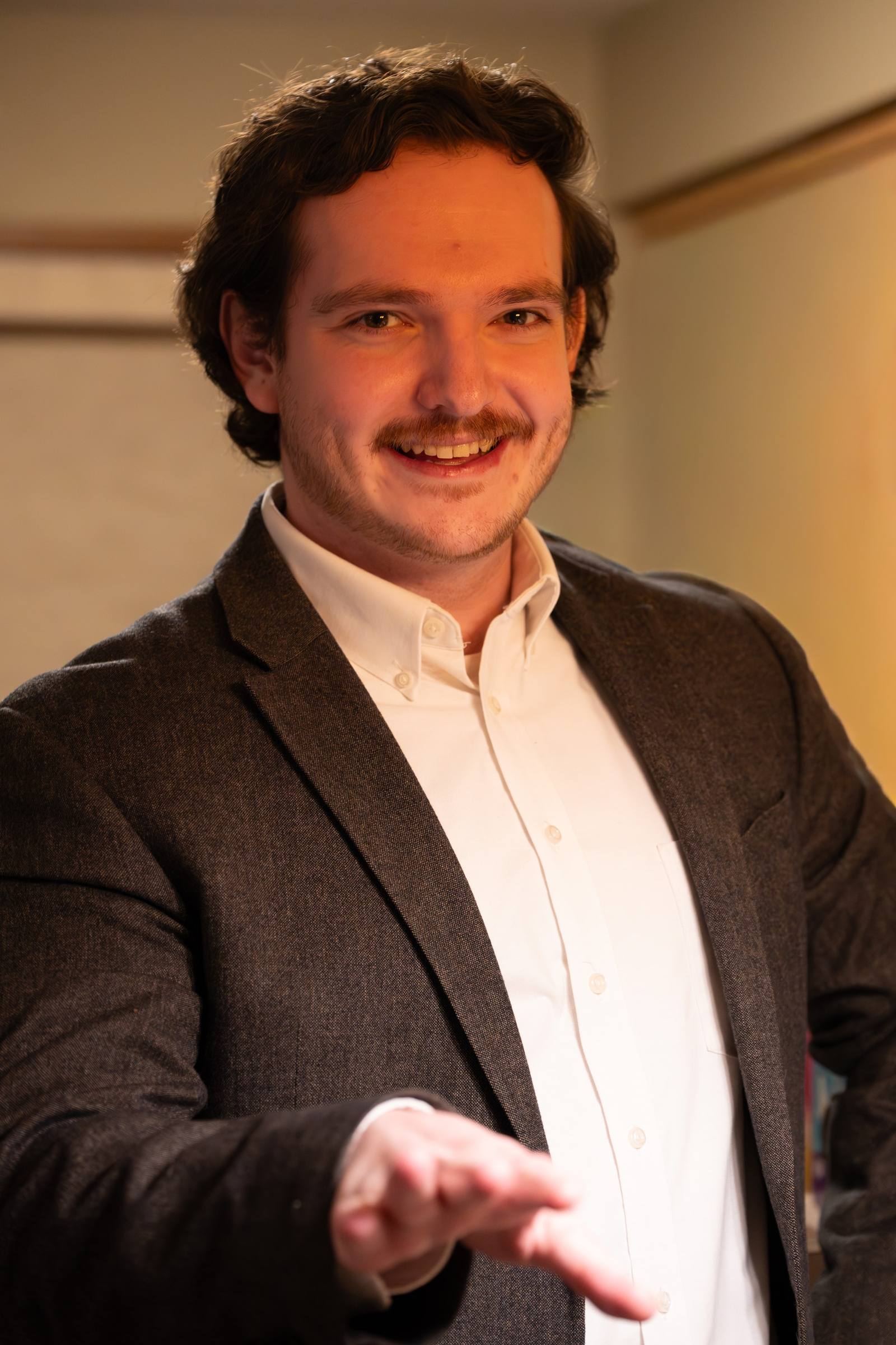 A cropped portrait of a person in a suit jacket and white shirt.