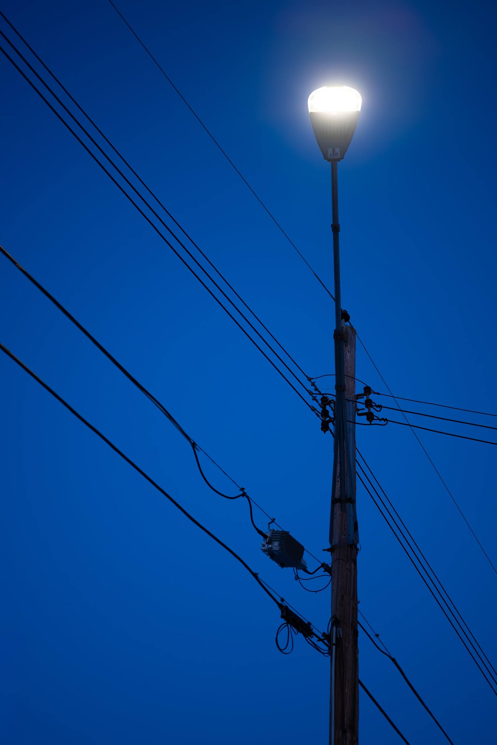 Power lines and a utility pole silhouetted against a deep blue sky.