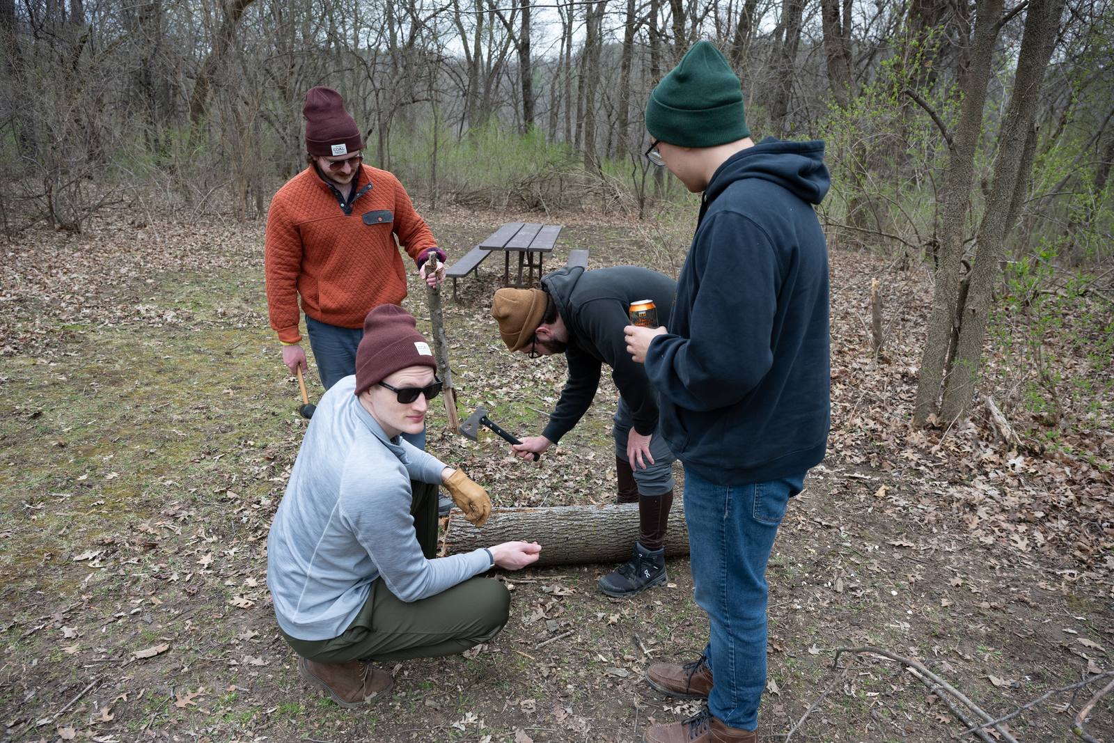 A small group gathers around gear on a wooded trail.